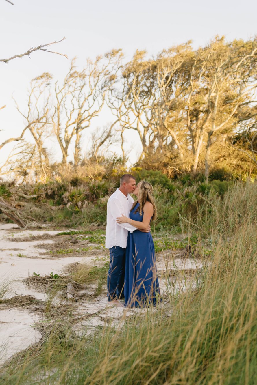 Couple kissing among the dune grass and windswept trees at Boneyard Beach, Big Talbot Island