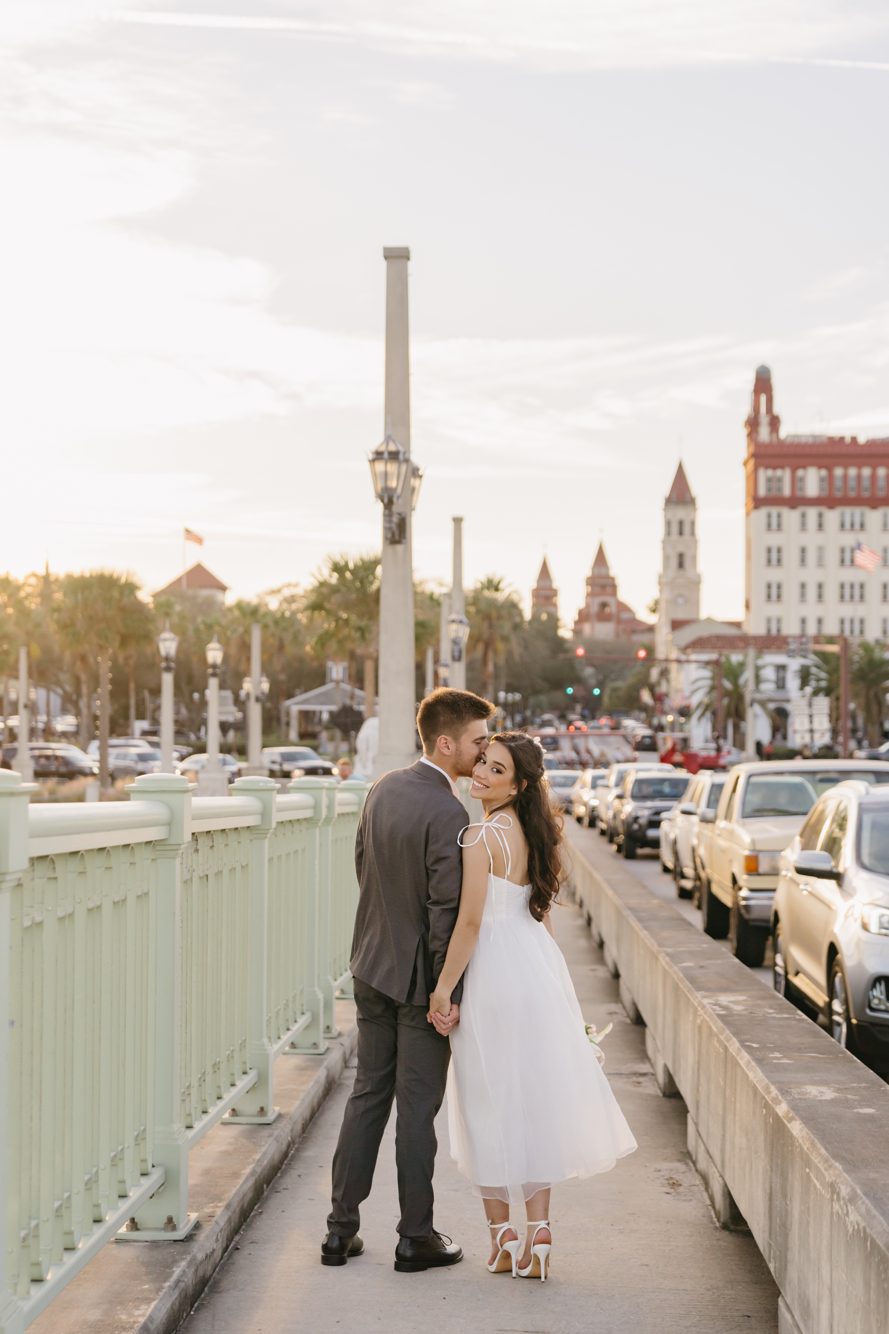 Couple embracing on the steps beneath the ornate arches of a historic church in downtown St. Augustine FL by Lee Photo + Video