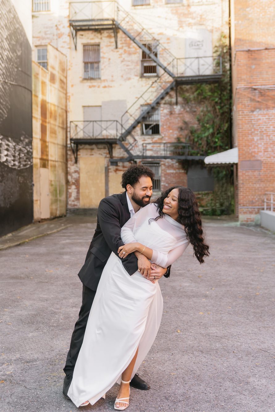 Couple holding hands crossing the brick streets of downtown Jacksonville near James Weldon Johnson Park by Lee Photo + Video