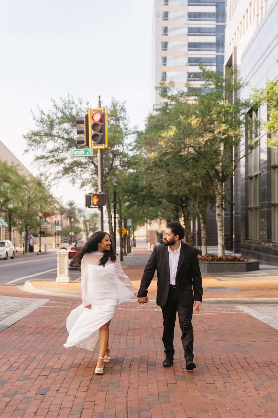 Couple embracing beside historic arched architecture in golden light, downtown Jacksonville FL