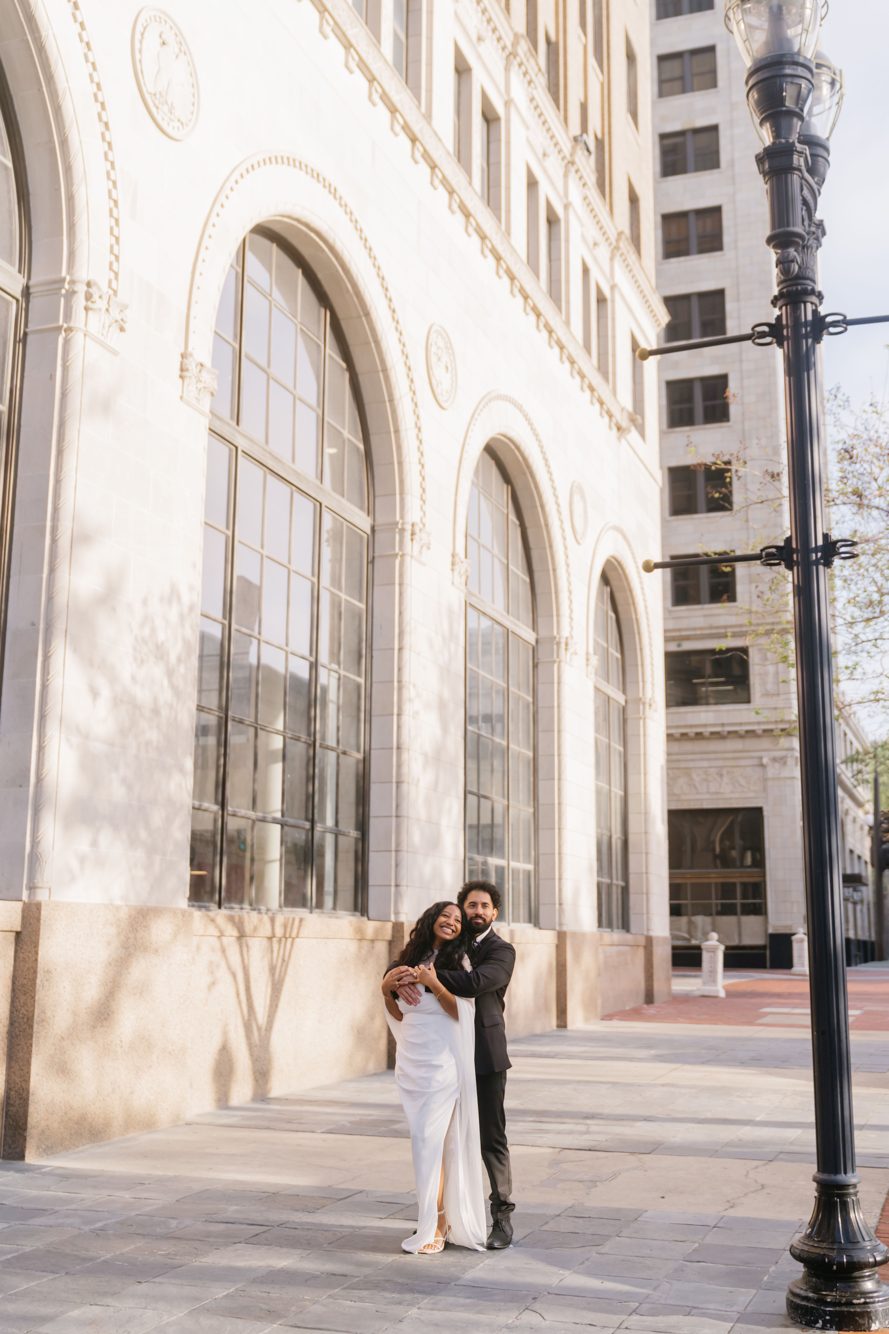 Couple laughing in a historic brick alley with fire escapes in downtown Jacksonville, Florida