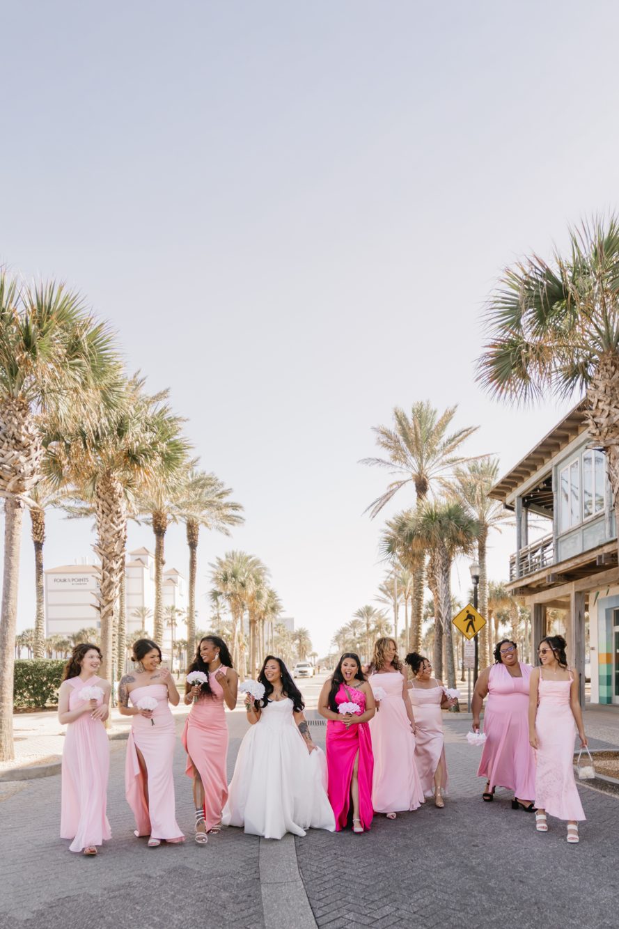 Bride and groom beneath the wooden awnings near the Jacksonville Beach Boardwalk with palm trees by Lee Photo + Video