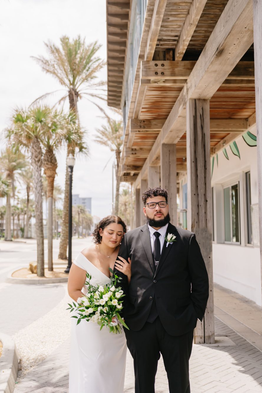 Senior portrait against white coastal architecture and palms near the Jacksonville Beach Boardwalk by Lee Photo + Video