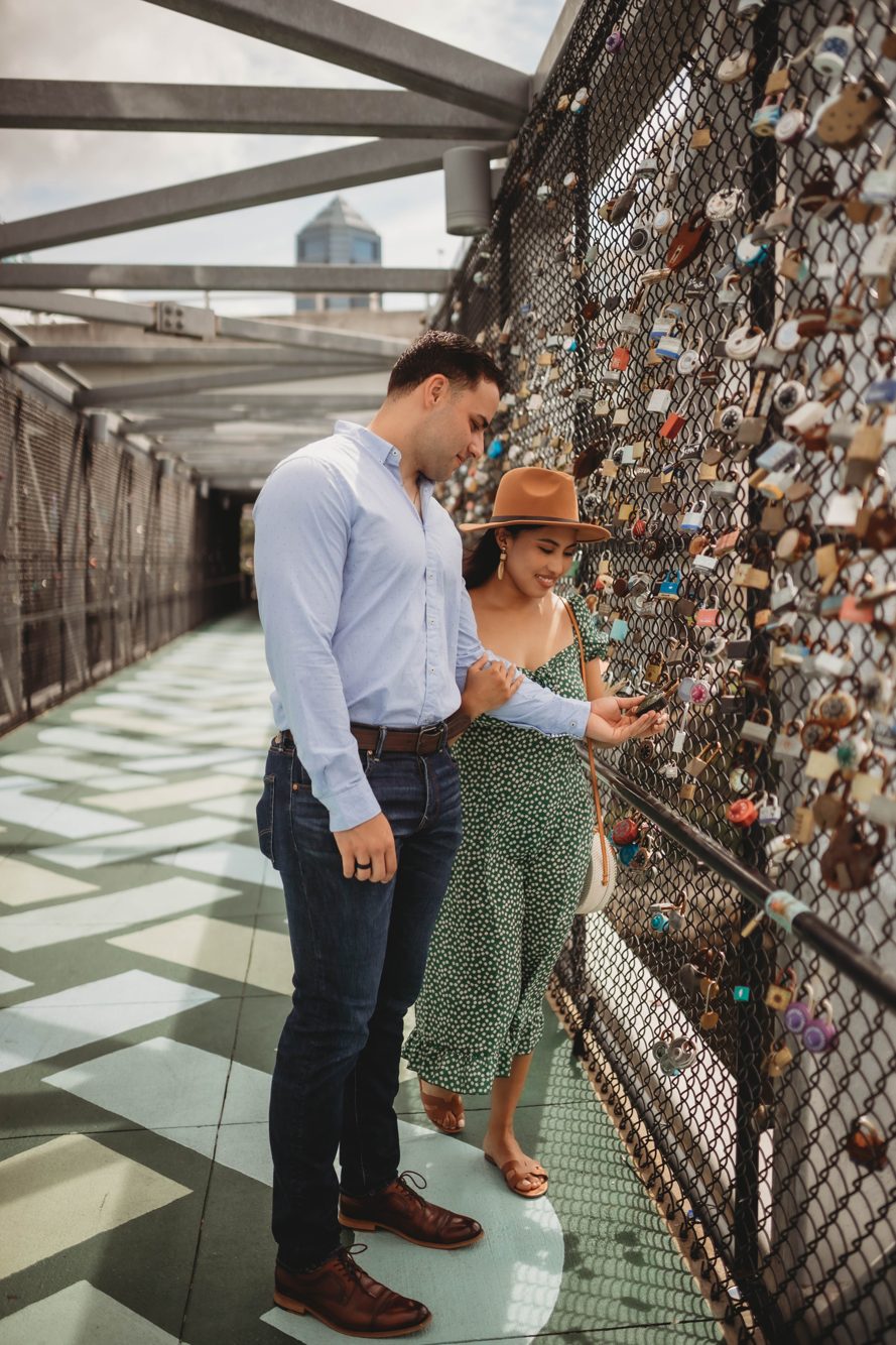 Couple embracing on the downtown Jacksonville riverwalk with the historic railroad bridge across the river by Lee Photo + Video