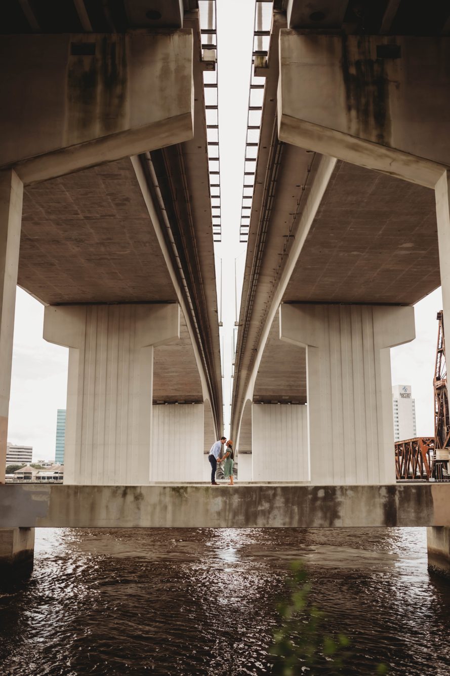 Couple kissing framed between the twin bridge spans over the St. Johns River in downtown Jacksonville FL