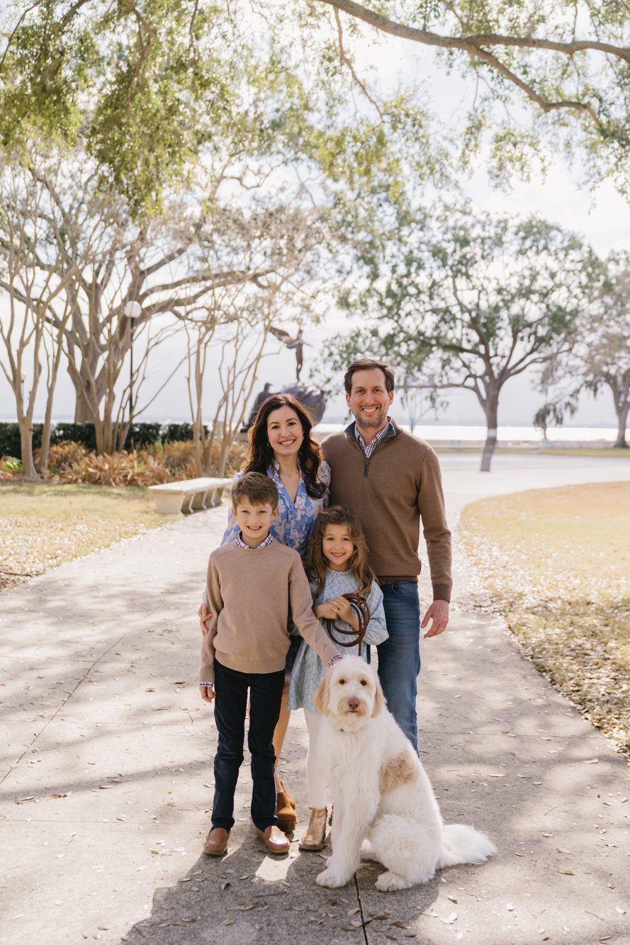 Family of four with their goldendoodle on the oak-lined path at Memorial Park in Riverside, Jacksonville FL by Lee Photo + Video