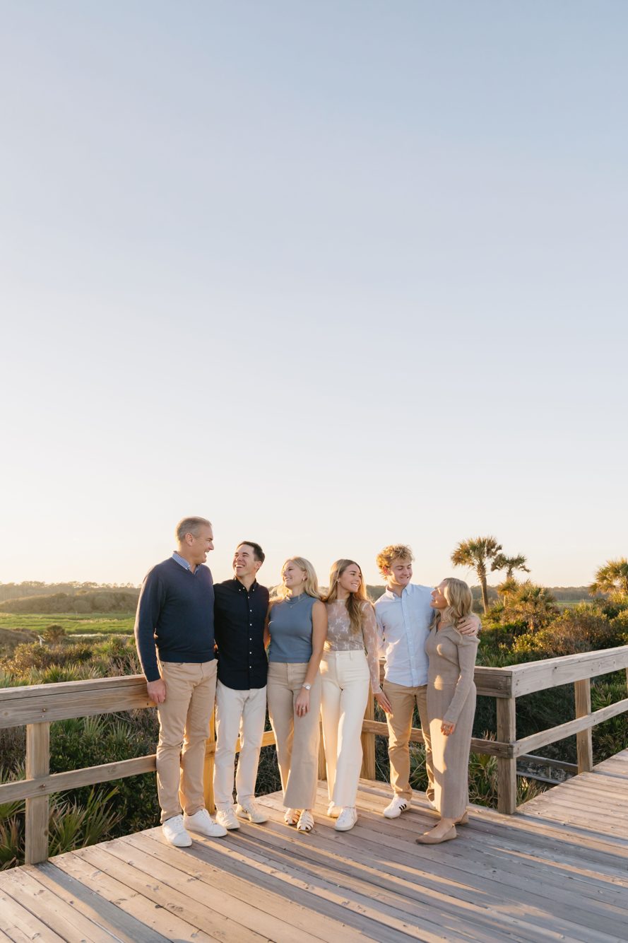 Family laughing together on the wooden dune walkover at golden hour, North Beach Guana State Park Florida