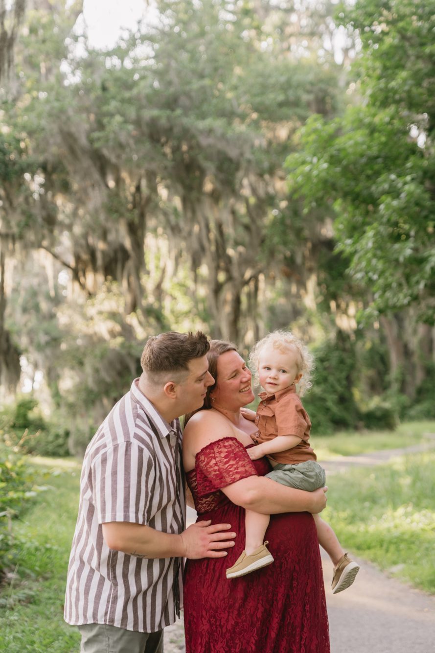Maternity session with mom holding her curly-haired toddler under the oaks at Riverfront Park by Lee Photo + Video
