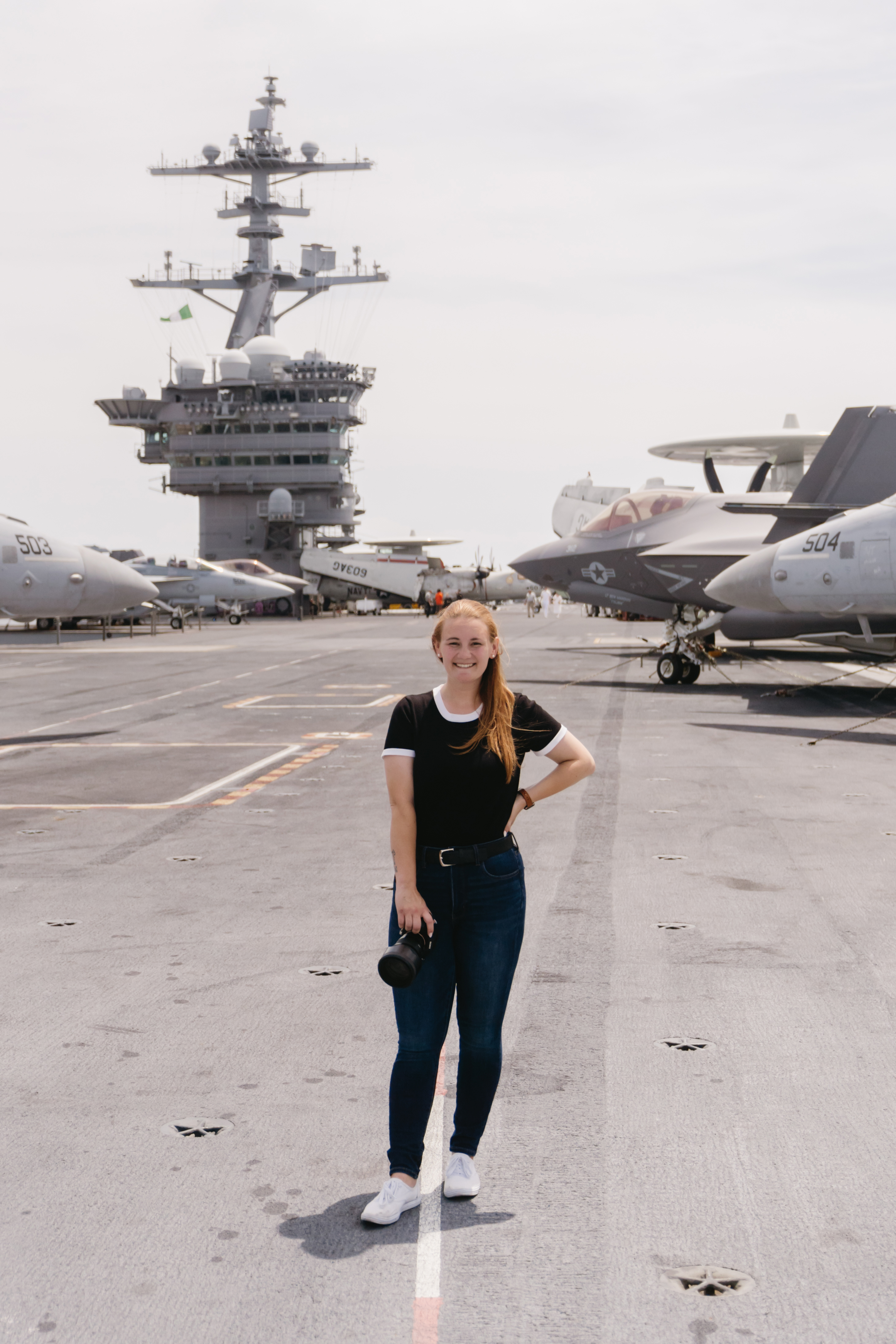 Sydney Lee photographer standing on aircraft carrier flight deck with camera