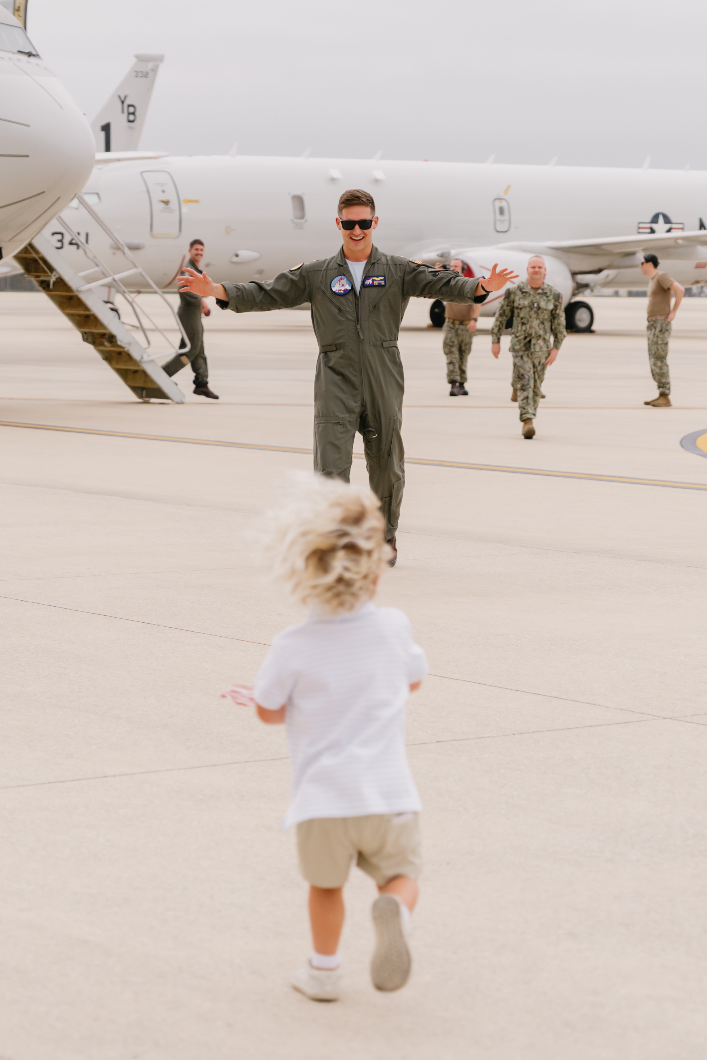 Child running across flight line toward returning Navy pilot at NAS Jacksonville homecoming