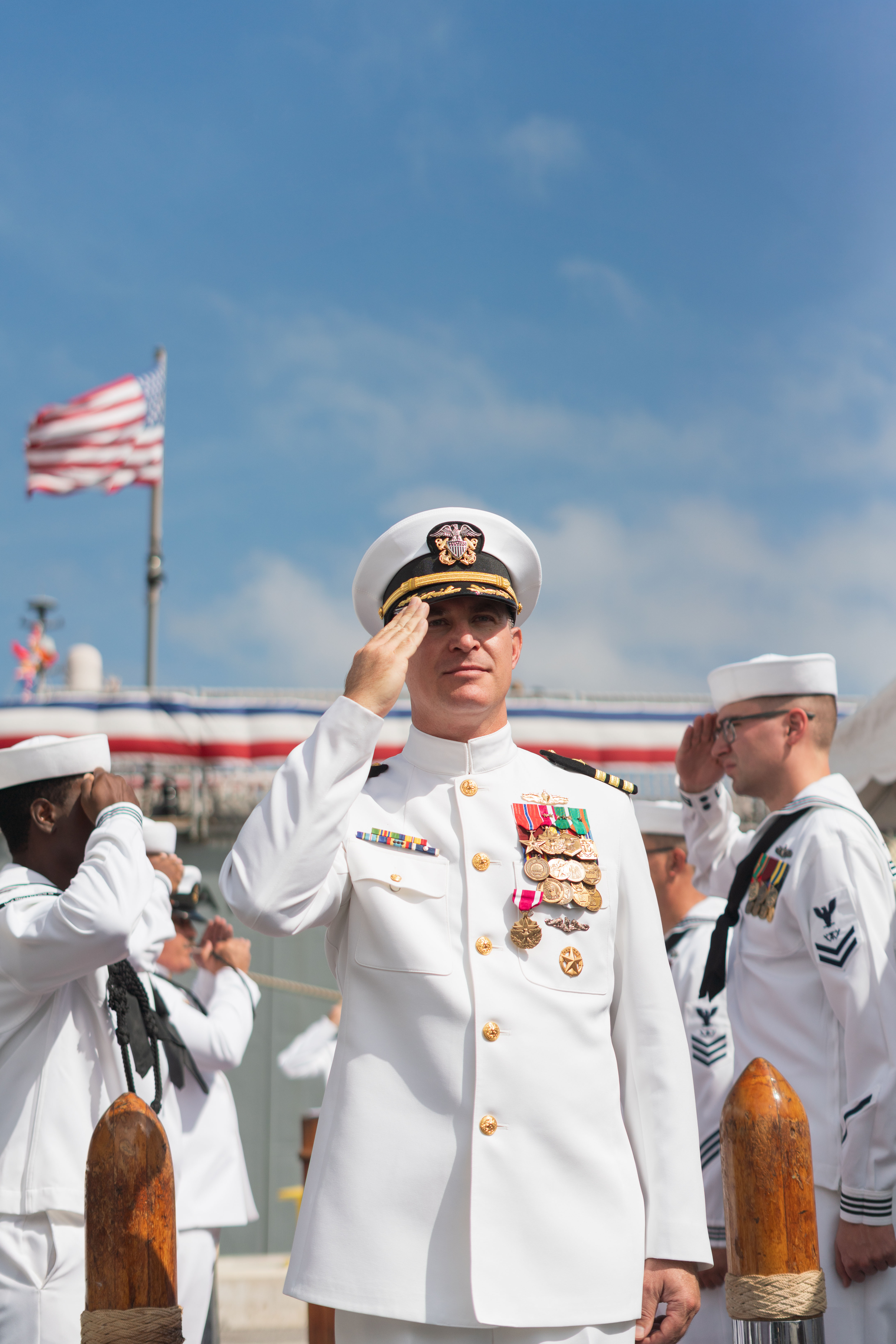 Navy change of command ceremony under giant American flag in hangar at NAS Jacksonville